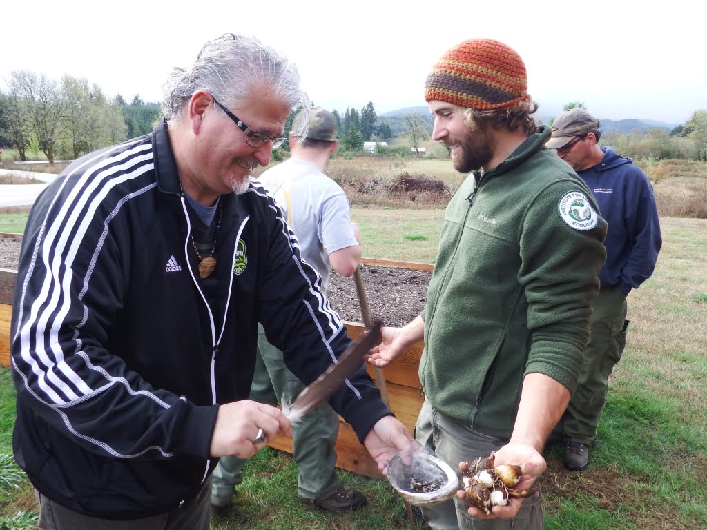 Tribal Council member Jon George blessing camas before planting at the raised beds at Grand Ronde