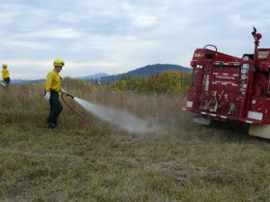 Wetting down the mowed fire line to control the perimeter of the fire.